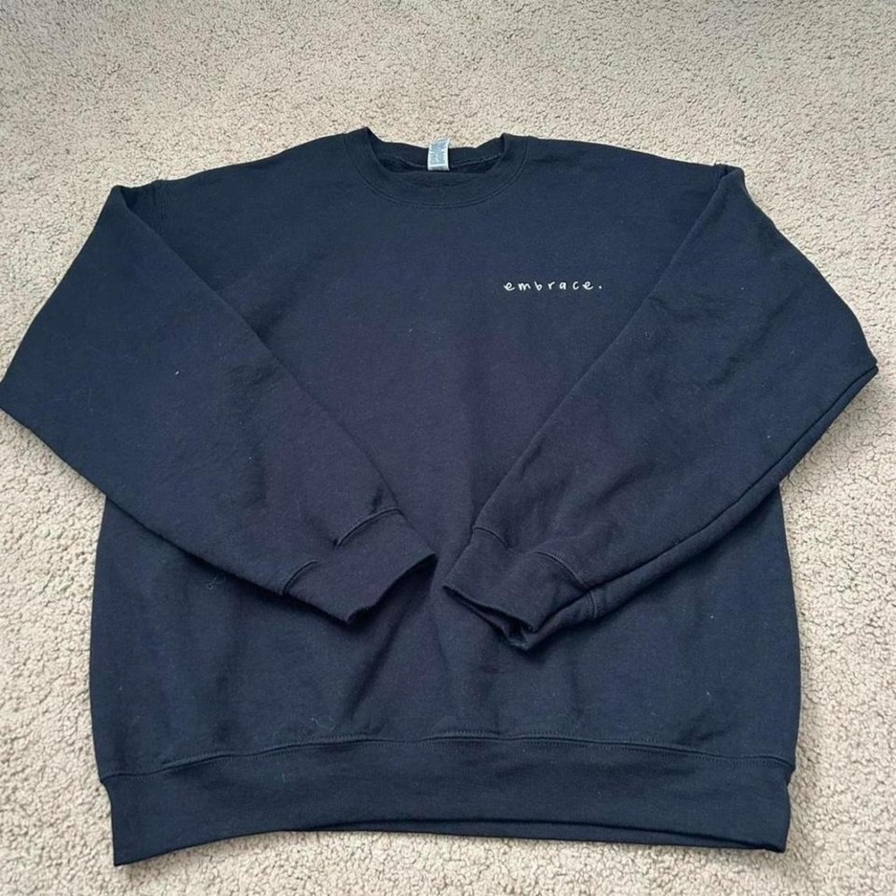 Black crewneck‎ sweatshirt with "embrace" embroidered on the front